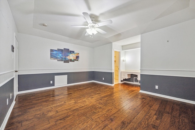 spare room featuring ceiling fan, dark hardwood / wood-style floors, and a raised ceiling