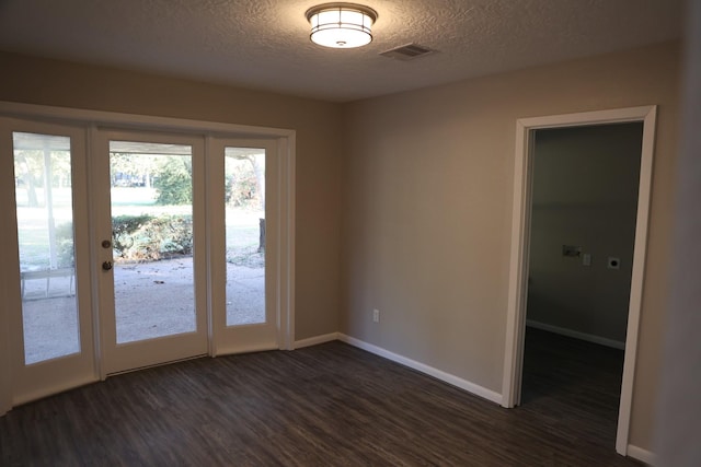 empty room featuring french doors, a textured ceiling, and dark hardwood / wood-style floors