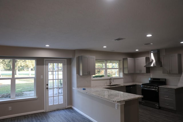 kitchen with dark wood-type flooring, black gas stove, sink, wall chimney exhaust hood, and kitchen peninsula