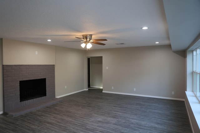 unfurnished living room featuring a fireplace, dark hardwood / wood-style flooring, and ceiling fan