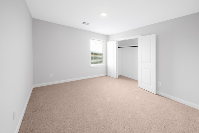 unfurnished bedroom with light carpet and a closet