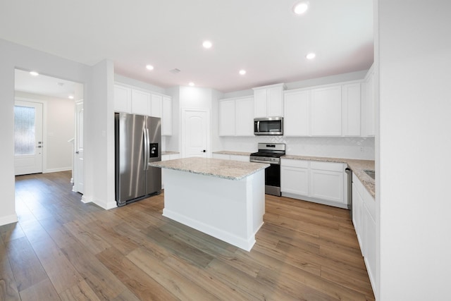 kitchen featuring white cabinets, a center island, appliances with stainless steel finishes, and light hardwood / wood-style flooring