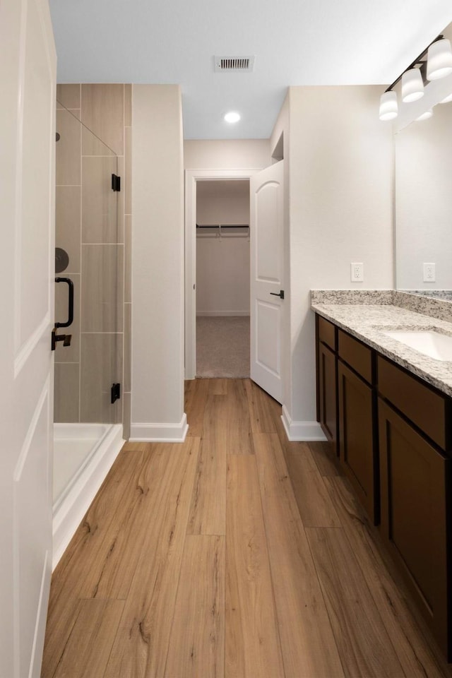 bathroom featuring a shower with door, vanity, and hardwood / wood-style flooring