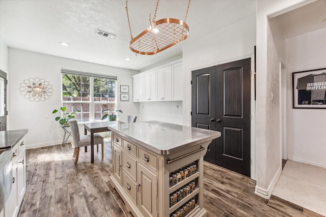 kitchen featuring white cabinetry, a kitchen island, light hardwood / wood-style floors, and a textured ceiling