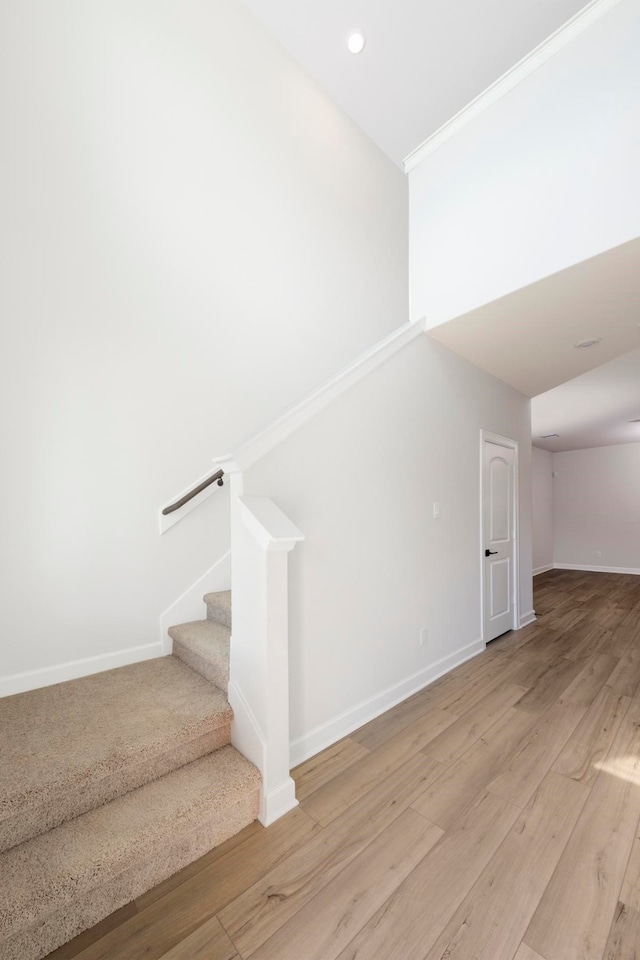 stairway featuring wood-type flooring and ornamental molding