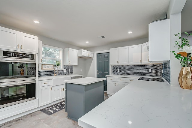 kitchen with white cabinets, a kitchen island, and stainless steel double oven