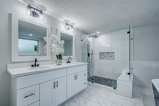 bathroom featuring vanity, a tile shower, and a textured ceiling