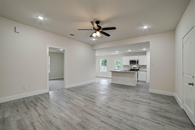 unfurnished living room with ceiling fan and light hardwood / wood-style flooring