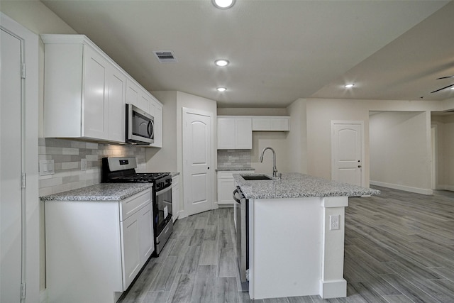 kitchen with sink, white cabinetry, stainless steel appliances, and an island with sink