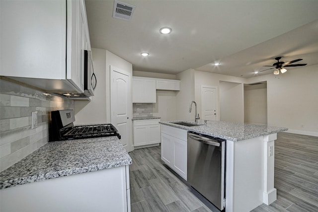 kitchen with sink, an island with sink, decorative backsplash, white cabinets, and appliances with stainless steel finishes