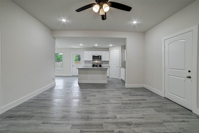 kitchen featuring a center island with sink, ceiling fan, light hardwood / wood-style floors, white cabinetry, and stainless steel appliances