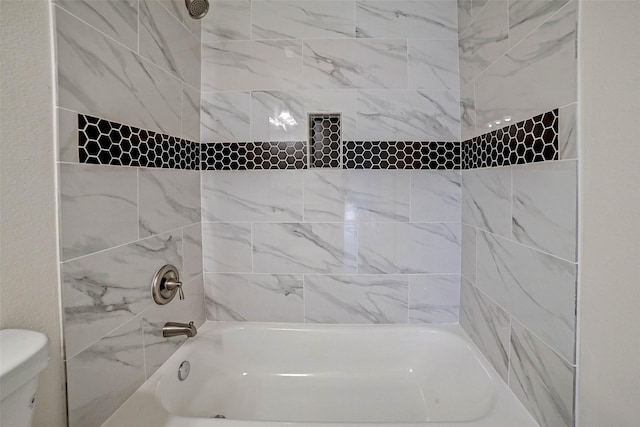 bathroom featuring toilet and tiled shower / bath