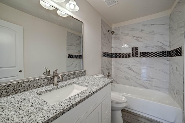 full bathroom featuring vanity, wood-type flooring, tiled shower / bath combo, and toilet