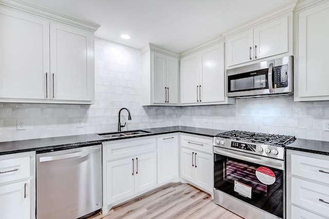 kitchen featuring stainless steel appliances, white cabinetry, tasteful backsplash, and sink