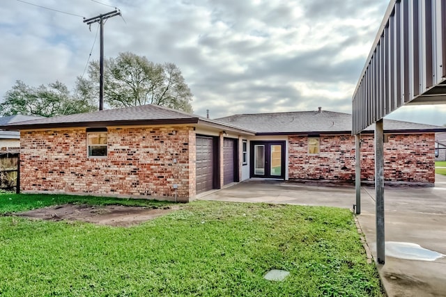 exterior space with a garage, a yard, and french doors