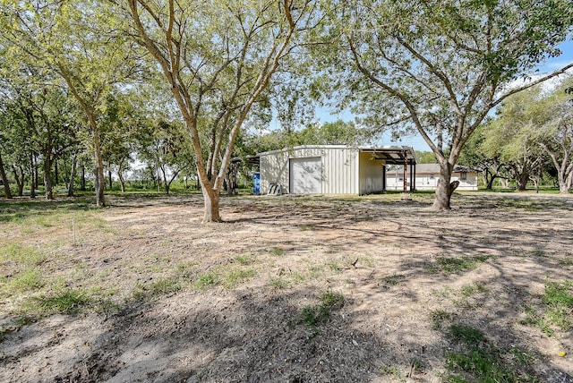 view of yard with a carport, a garage, and an outbuilding