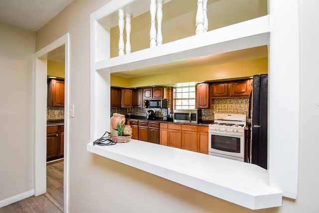 kitchen featuring backsplash, hanging light fixtures, white gas stove, and light hardwood / wood-style floors