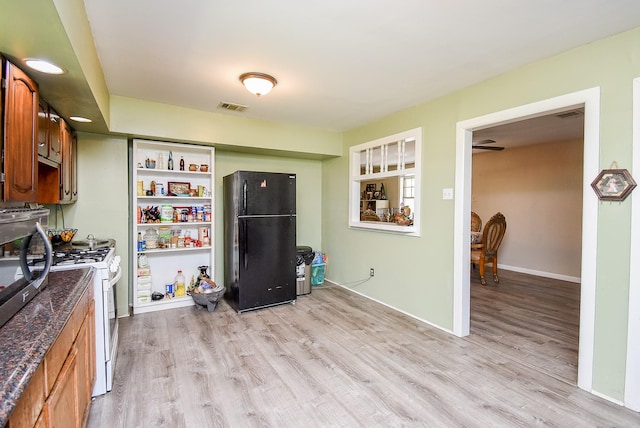 kitchen with white gas range, black fridge, light hardwood / wood-style flooring, and dark stone countertops