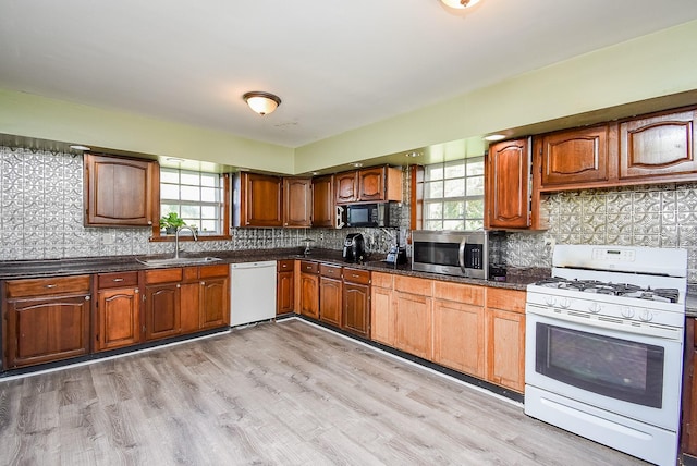 kitchen featuring plenty of natural light, light wood-type flooring, white appliances, and sink