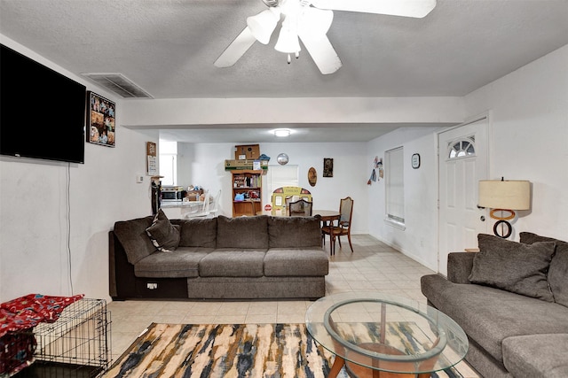 living room with a textured ceiling, ceiling fan, and light tile patterned flooring