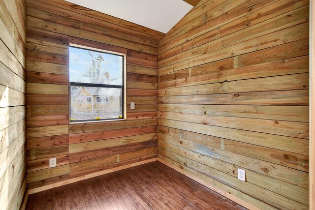 empty room featuring dark hardwood / wood-style floors, wood walls, and vaulted ceiling