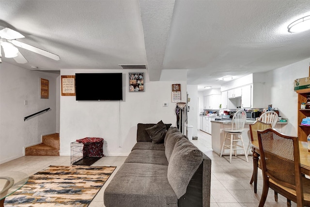 tiled living room with a textured ceiling and ceiling fan