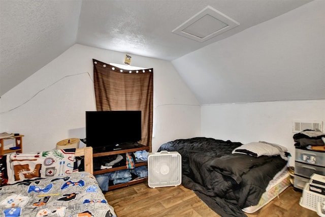 bedroom with hardwood / wood-style floors, a textured ceiling, and vaulted ceiling