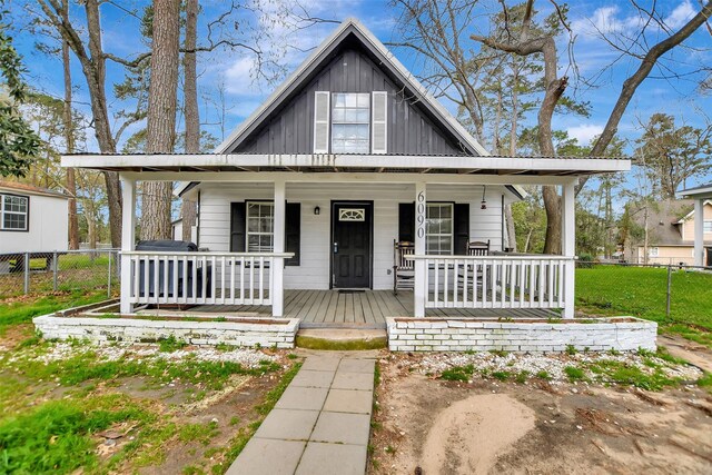 view of front of house with covered porch, board and batten siding, and fence