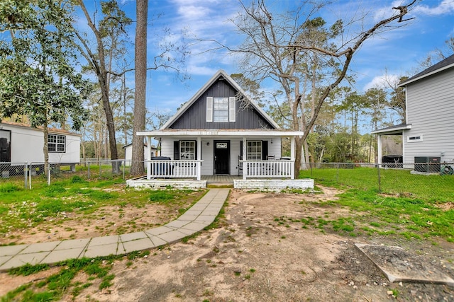 view of front of property with a porch, fence, cooling unit, board and batten siding, and a front yard