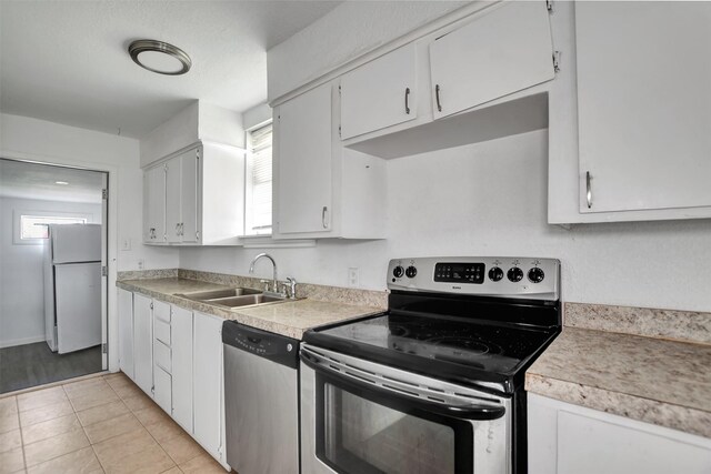 kitchen featuring light countertops, light tile patterned floors, white cabinets, stainless steel appliances, and a sink