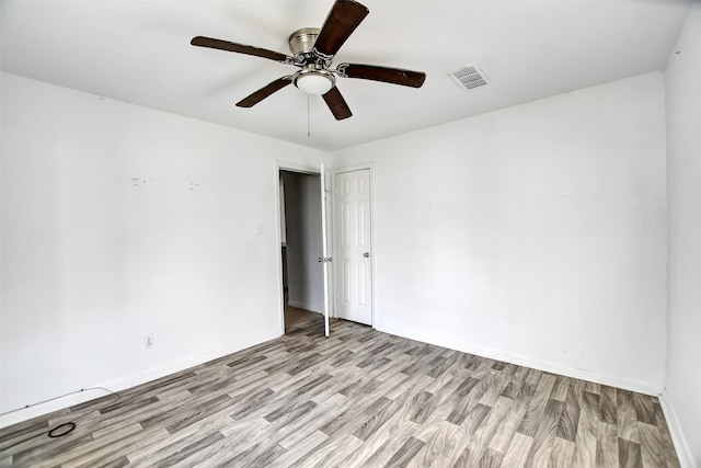 empty room with light wood finished floors, visible vents, baseboards, and ceiling fan