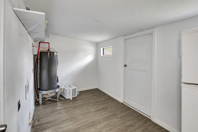 basement with water heater, freestanding refrigerator, baseboards, and wood finished floors