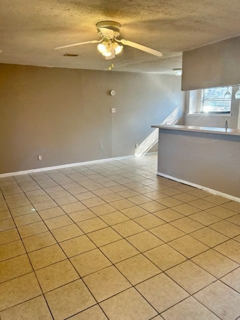 tiled empty room featuring ceiling fan and a textured ceiling