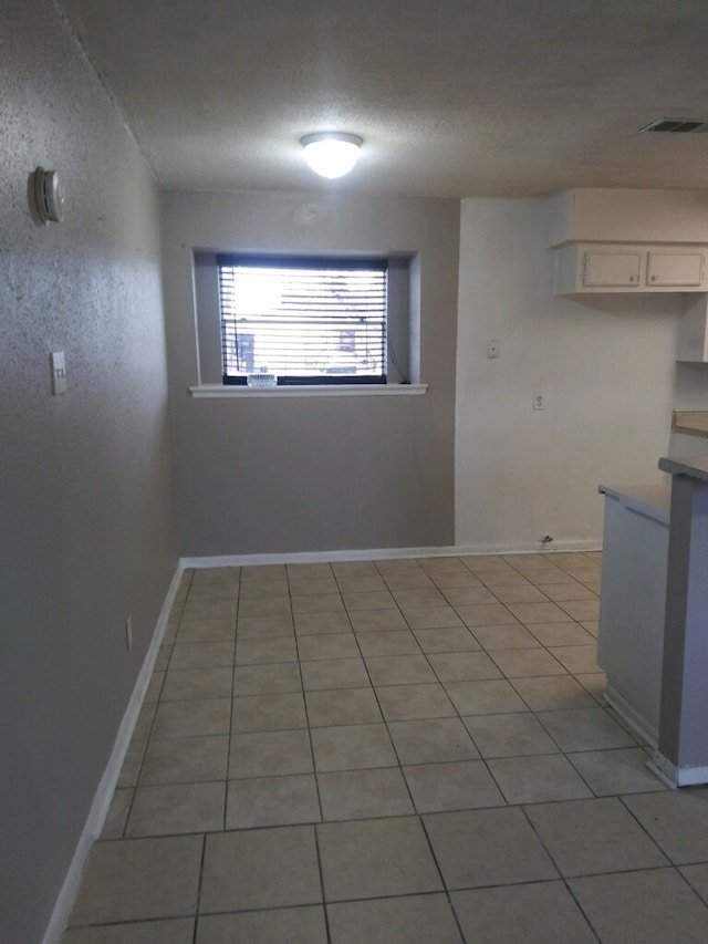 unfurnished dining area with light tile patterned floors and a textured ceiling