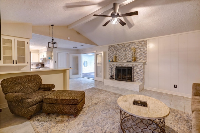 living room with ceiling fan, a textured ceiling, wooden walls, a fireplace, and light tile patterned flooring