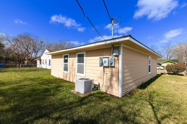 view of side of property featuring central AC unit and a lawn