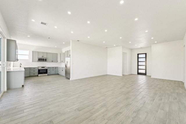 unfurnished living room featuring sink and light hardwood / wood-style floors