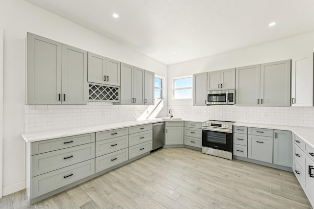 kitchen featuring decorative backsplash, sink, light hardwood / wood-style flooring, and appliances with stainless steel finishes