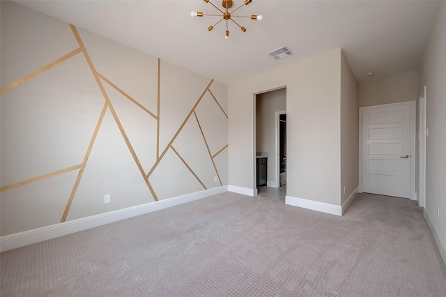 carpeted empty room featuring a chandelier