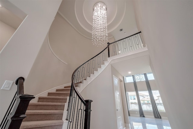 stairway with a towering ceiling and a notable chandelier