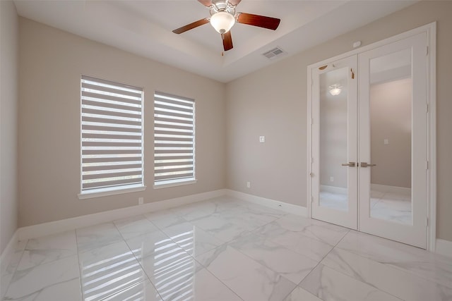 empty room featuring french doors, a raised ceiling, and ceiling fan