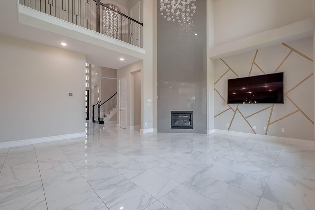 unfurnished living room with a tiled fireplace and a towering ceiling