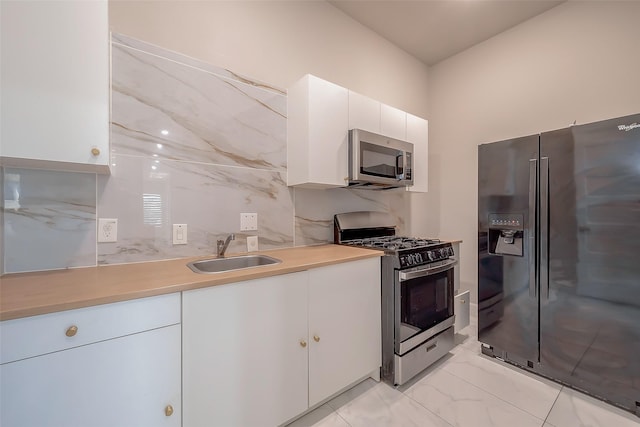 kitchen featuring white cabinets, sink, appliances with stainless steel finishes, and tasteful backsplash