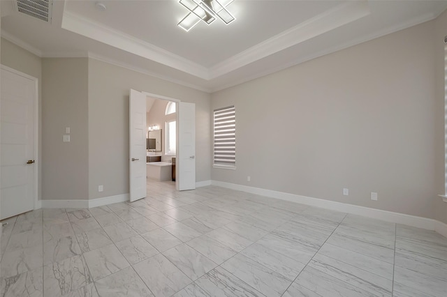 empty room featuring a tray ceiling and crown molding