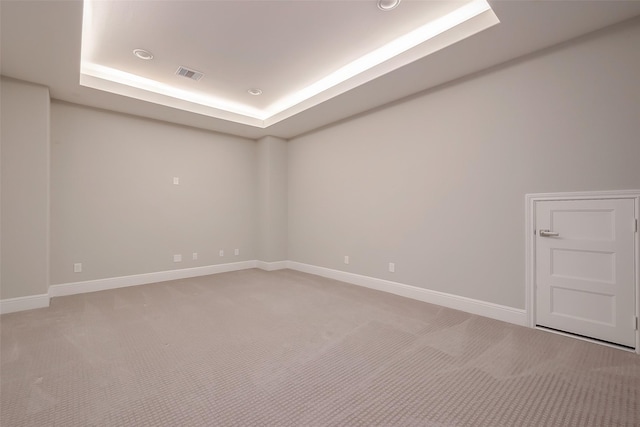 spare room featuring carpet flooring and a raised ceiling