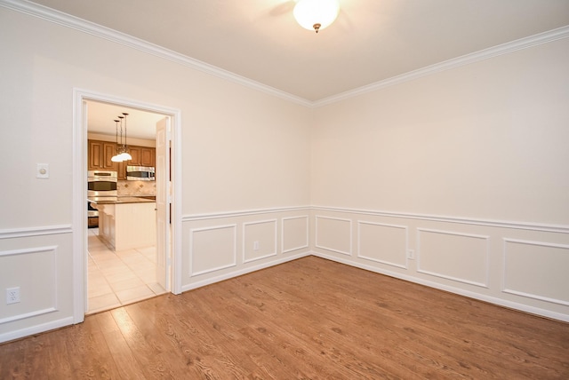 empty room with crown molding and light hardwood / wood-style flooring