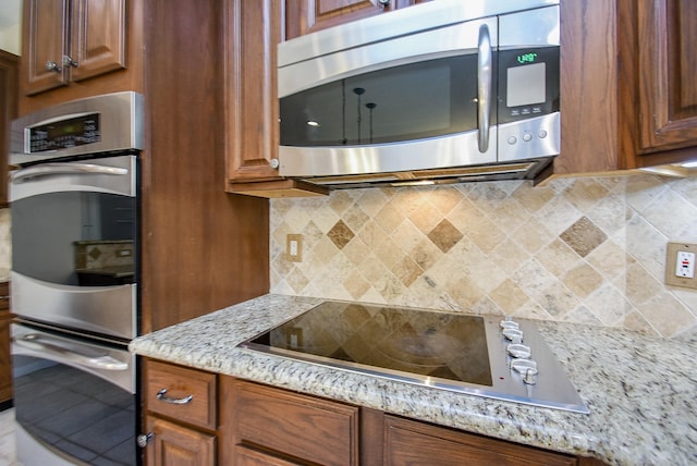 kitchen with light stone counters, stainless steel appliances, and tasteful backsplash