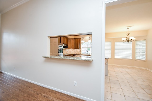 kitchen featuring sink, backsplash, stainless steel appliances, light stone countertops, and kitchen peninsula