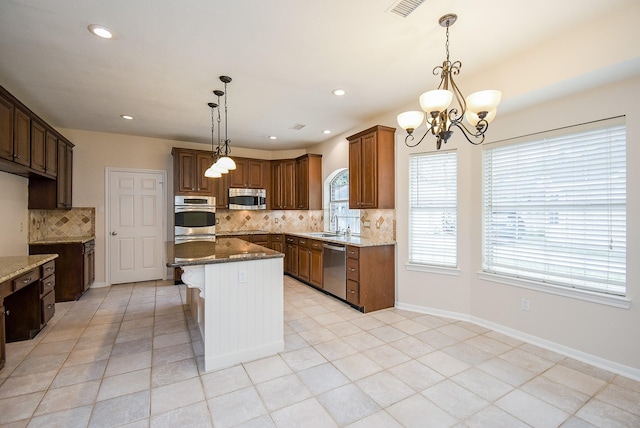 kitchen with stainless steel appliances, sink, decorative light fixtures, and dark stone counters