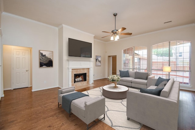 living room featuring ceiling fan, plenty of natural light, crown molding, and a tiled fireplace